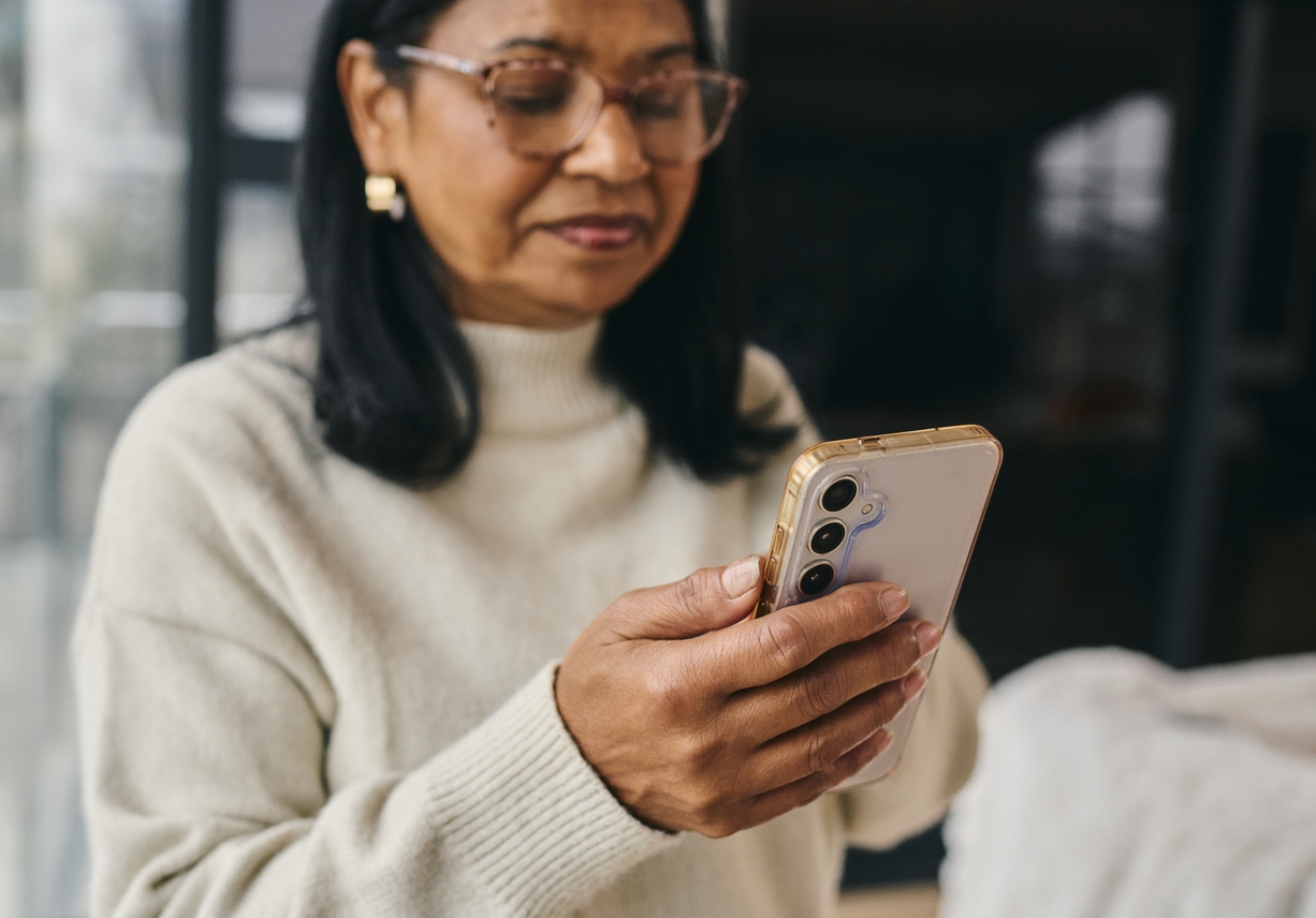 A woman checking her payment on a mobile phone at home